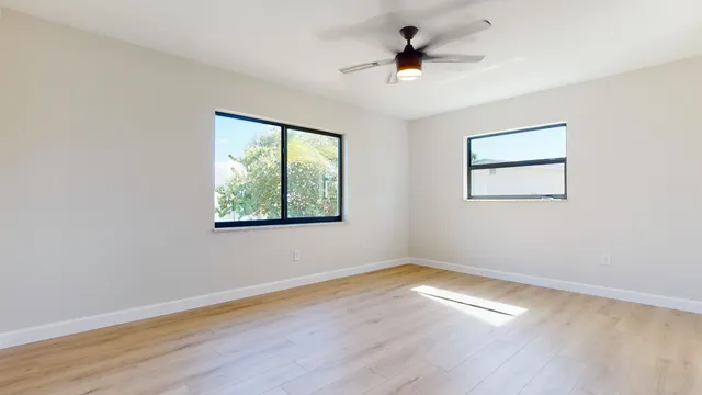an empty room with wooden floor and windows