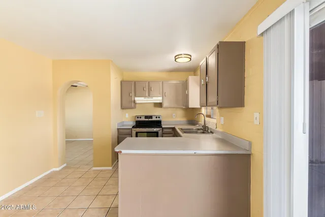 a kitchen with stainless steel appliances a refrigerator a sink a stove and white cabinets