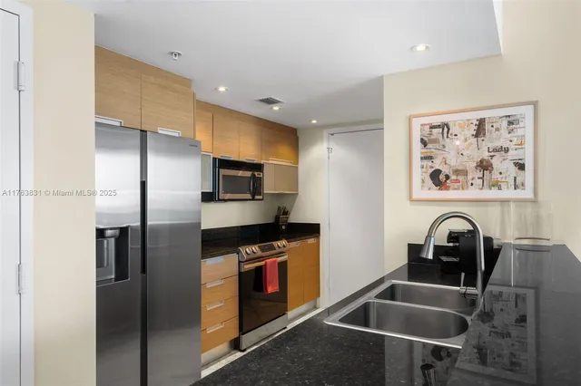 a kitchen with granite countertop a sink stainless steel appliances and cabinets