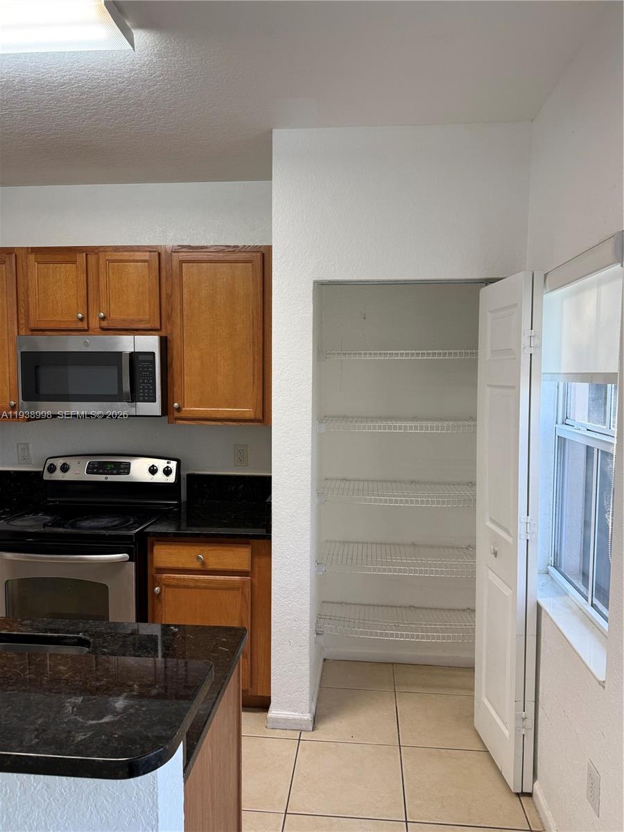 12260 Southwest 27th Street, Unit 1303 Miramar, FL 33025 - Photo 13 of 58 a kitchen with granite countertop a stove and a microwave