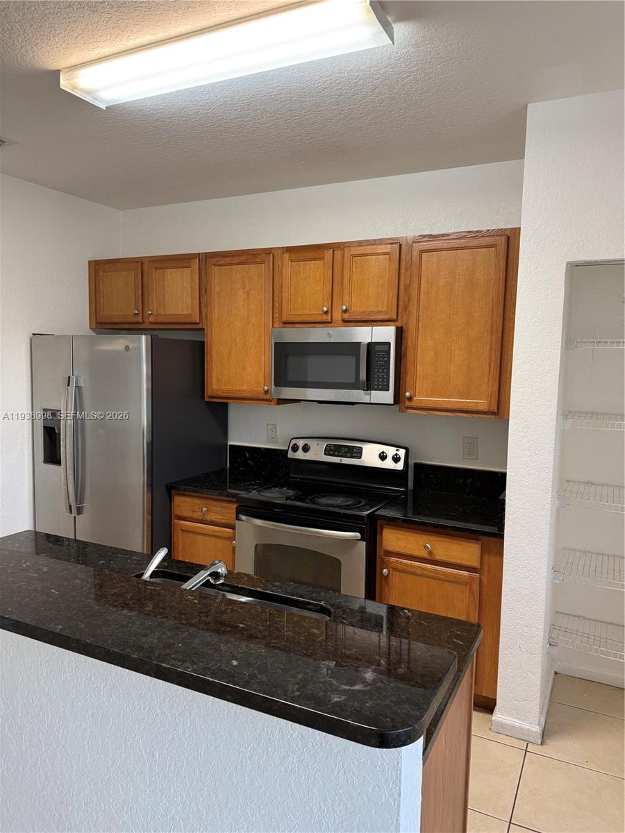 12260 Southwest 27th Street, Unit 1303 Miramar, FL 33025 - Photo 52 of 58 a kitchen with granite countertop a stove and a refrigerator