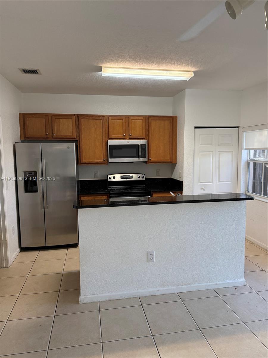 12260 Southwest 27th Street, Unit 1303 Miramar, FL 33025 - Photo 58 of 58 a kitchen with a refrigerator and cabinets