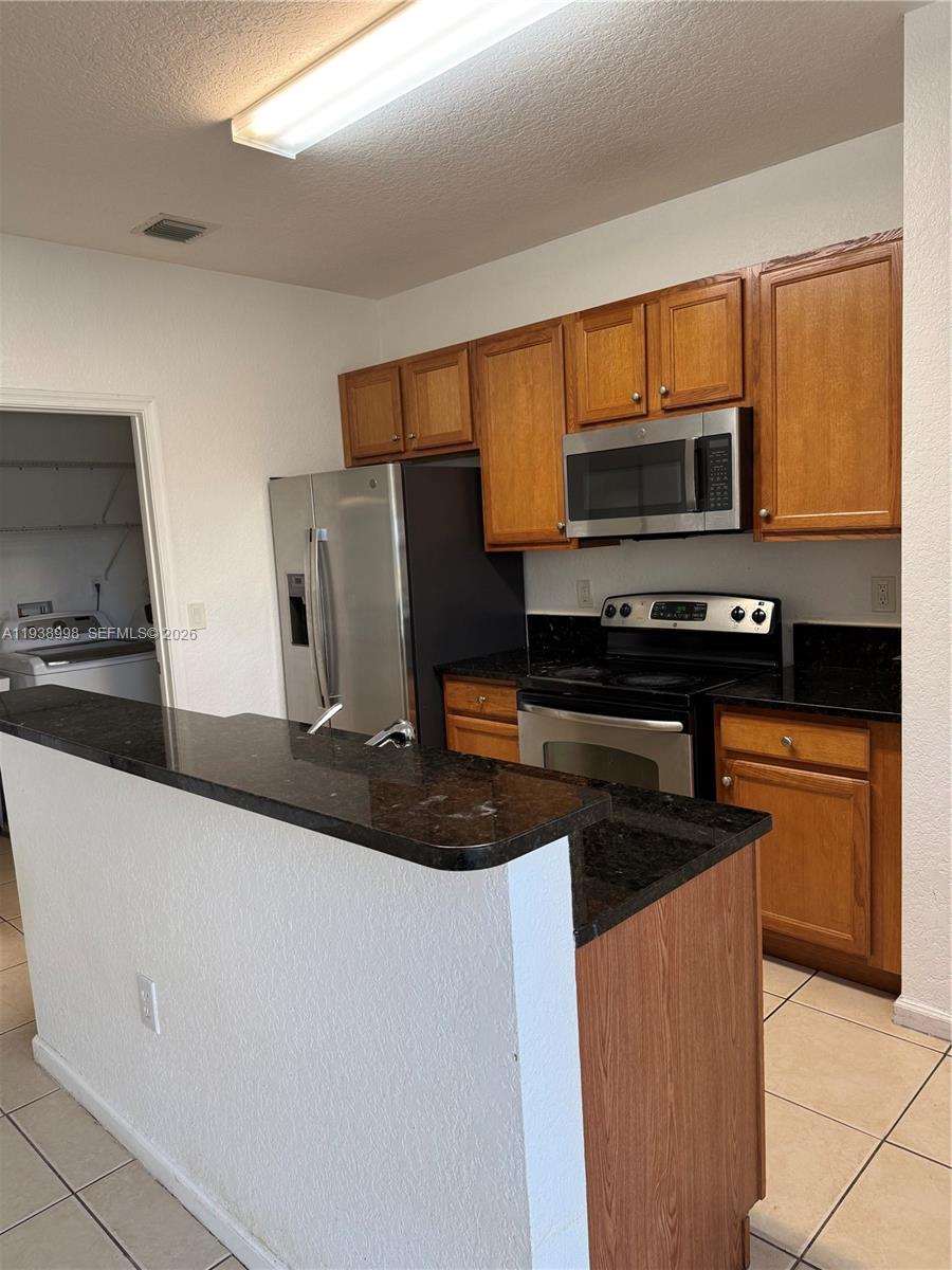 12260 Southwest 27th Street, Unit 1303 Miramar, FL 33025 - Photo 9 of 58 a kitchen with stainless steel appliances a stove microwave and refrigerator