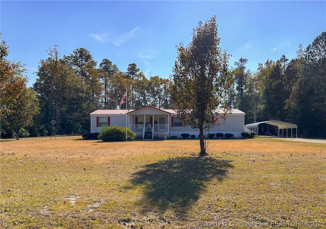 259 Burch Road Lumberton, NC 28360 - Photo 2 of 13 a street view with large trees and a wooden fence