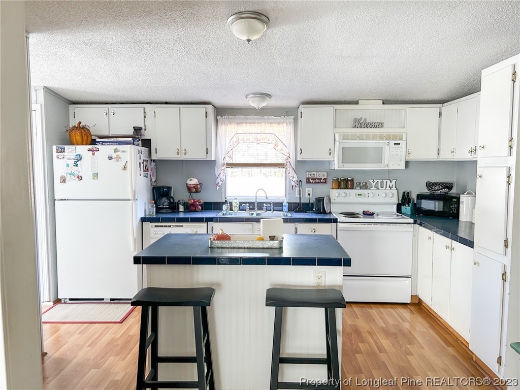 259 Burch Road Lumberton, NC 28360 - Photo 8 of 13 a kitchen with kitchen island white cabinets and refrigerator