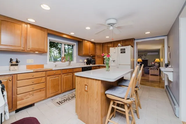 a kitchen with a stove a sink a kitchen island with chairs and wooden cabinets