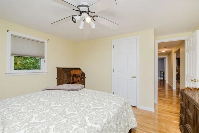 a bedroom with a bed and a dresser with wooden floor
