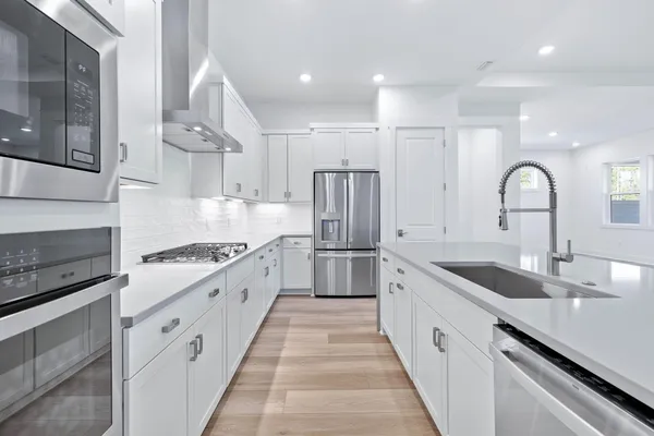 a large kitchen with stainless steel appliances granite countertop a lot of counter space and wooden floors