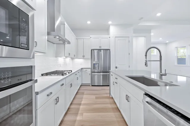 a large kitchen with stainless steel appliances granite countertop a lot of counter space and wooden floors