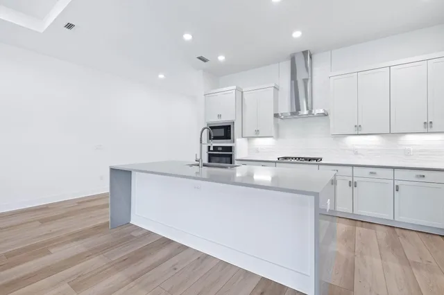 a kitchen with stainless steel appliances granite countertop a stove a sink and white cabinets