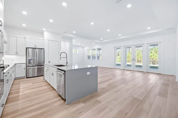 a large kitchen with stainless steel appliances granite countertop a large counter top a sink and a refrigerator