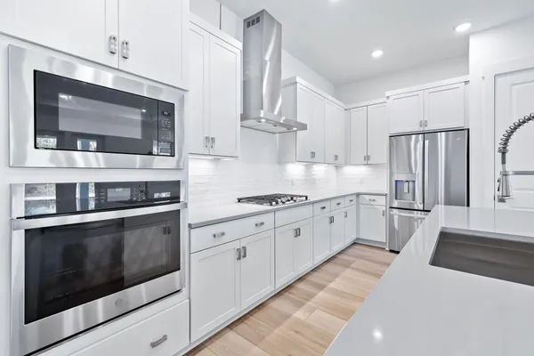 a kitchen with stainless steel appliances white cabinets a stove a sink and a microwave