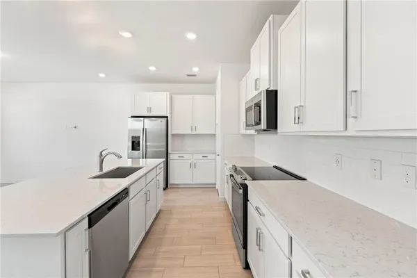 a kitchen with stainless steel appliances granite countertop a sink and dishwasher a stove top oven with wooden floor