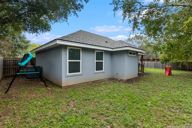a backyard of a house with plants and a tree