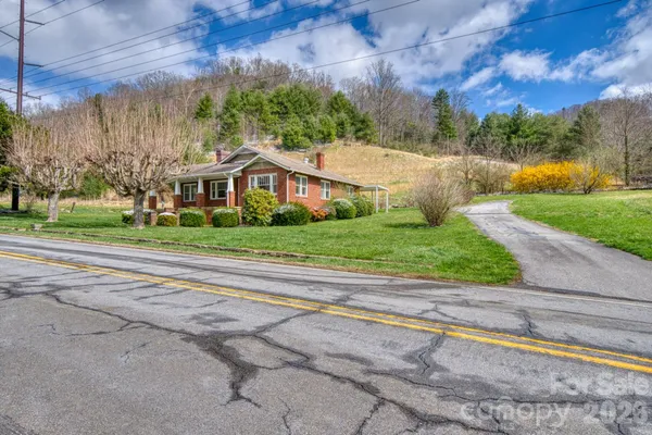 a view of a house with a yard and large trees