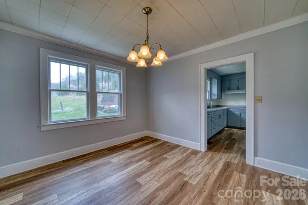 a view of a room with wooden floor chandelier and windows