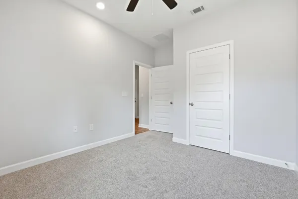 an empty room with closet and a chandelier fan