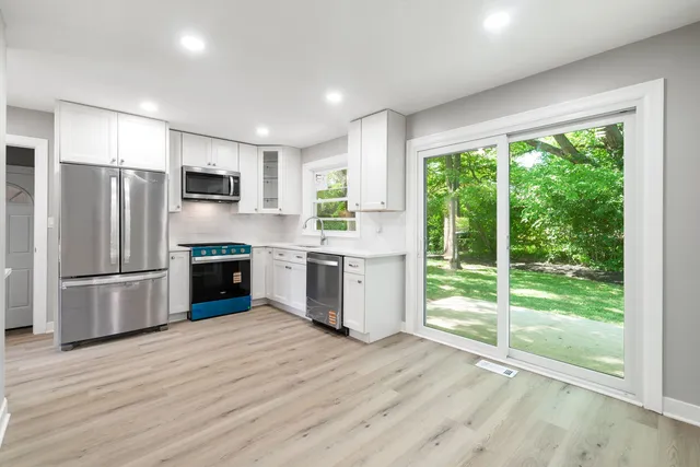a kitchen with a refrigerator a stove top oven and a large window