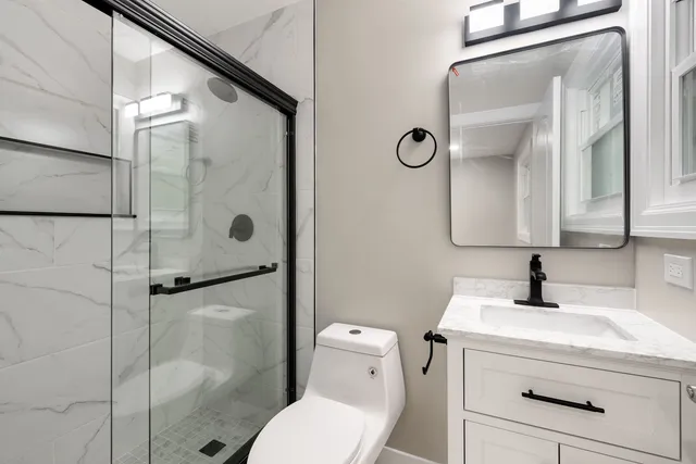 a bathroom with a toilet sink vanity and shower