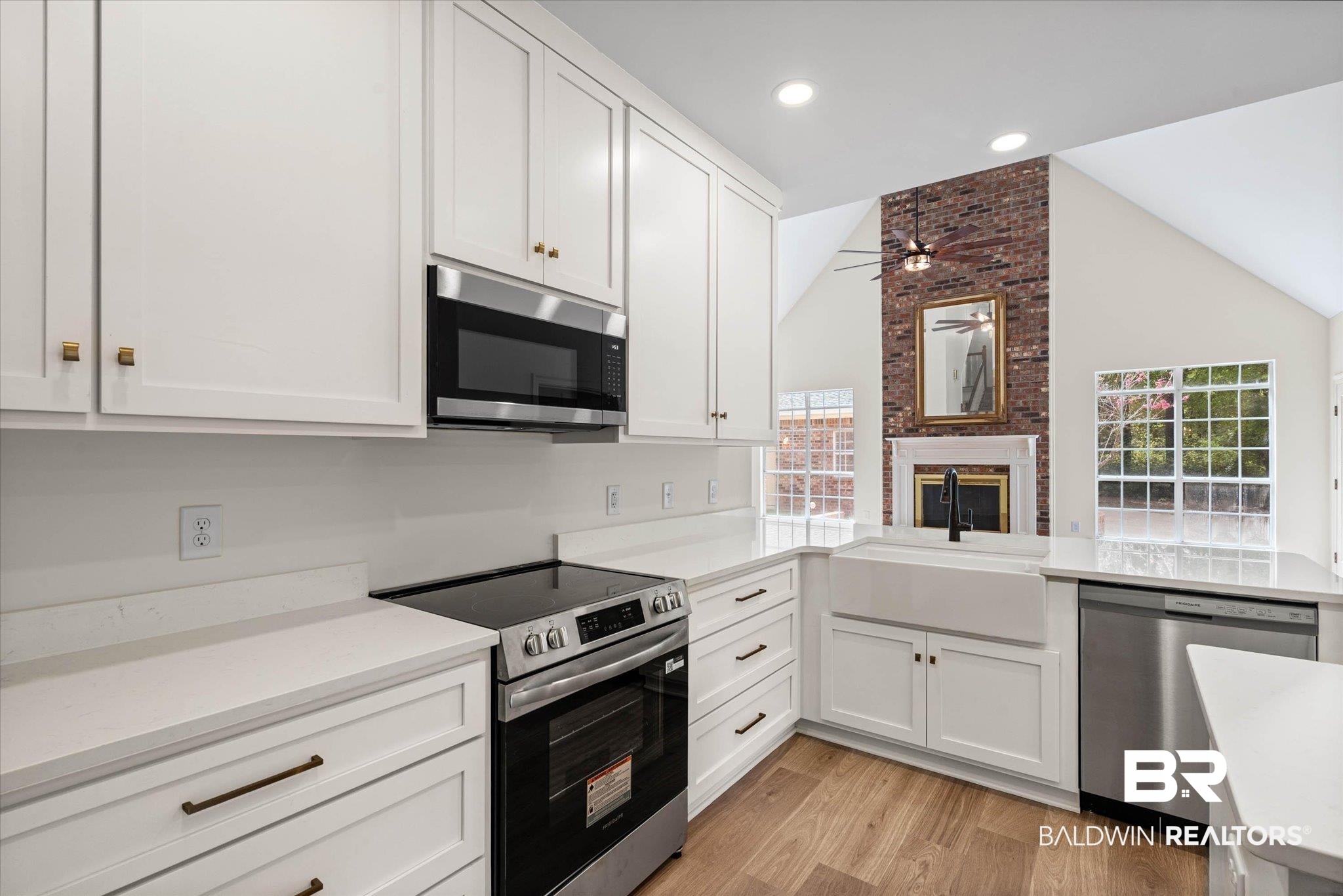 3451 Lacoste Road Mobile, AL 36618 - Photo 14 of 36 Kitchen featuring stainless steel appliances, white cabinetry, a brick fireplace, light wood-style floors, and a peninsula