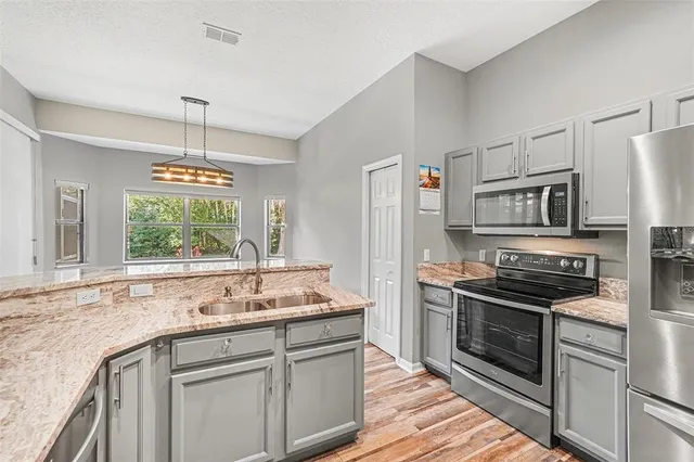 a kitchen with stainless steel appliances kitchen island granite countertop a refrigerator and a stove top oven