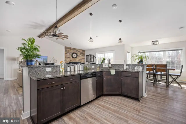 a kitchen with stainless steel appliances granite countertop a refrigerator a stove and a sink with wooden floor