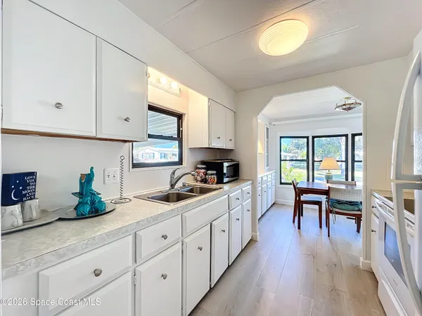 a kitchen with stainless steel appliances granite countertop a stove a sink dishwasher and white cabinets with wooden floor
