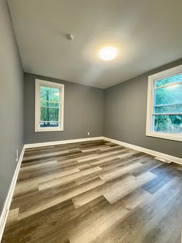 a view of empty room with wooden floor and window