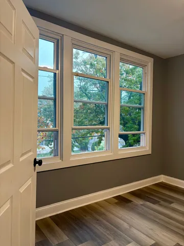 a view of empty room with wooden floor and fan