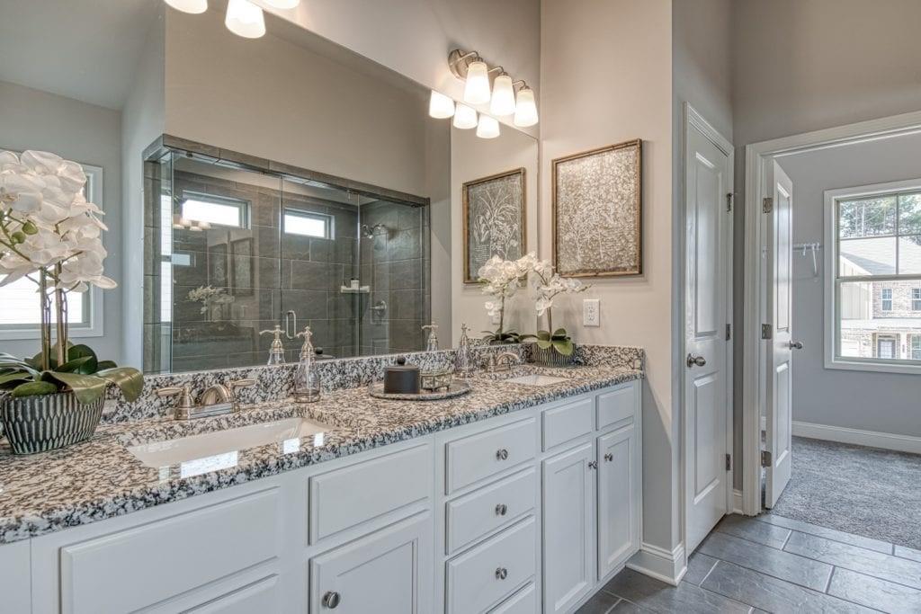 663 Secret Garden Lane Dacula, GA 30019 - Photo 22 of 27 a bathroom with double vanity sinks a vanity a lamp and a large mirror