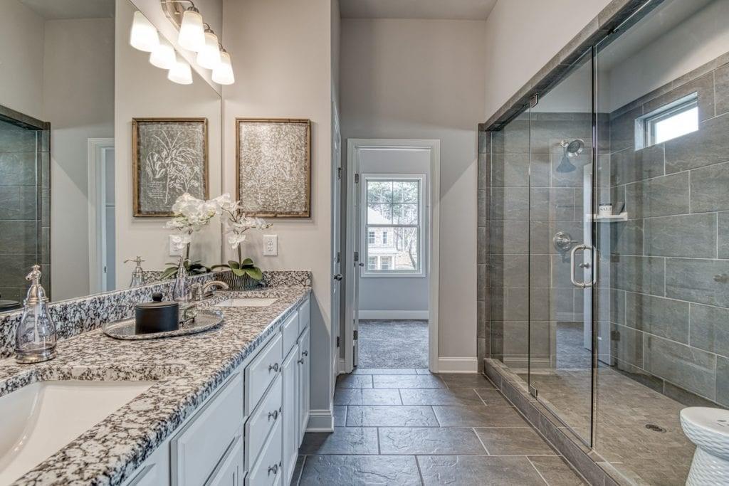 663 Secret Garden Lane Dacula, GA 30019 - Photo 23 of 27 a bathroom with a granite countertop sink a mirror and a shower
