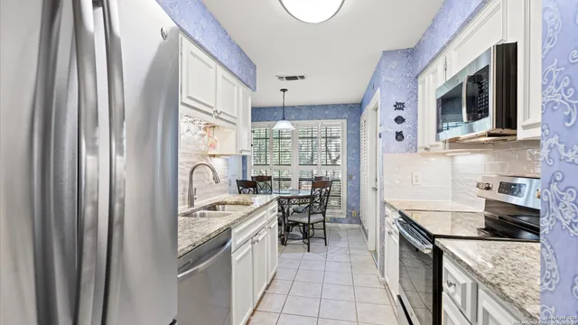 a kitchen with stainless steel appliances granite countertop a stove a sink and a microwave