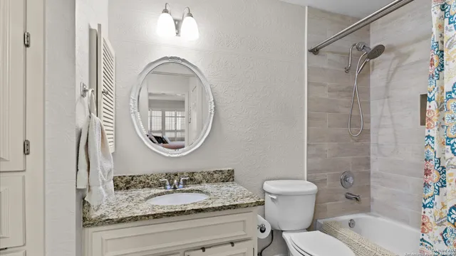a bathroom with a granite countertop toilet a sink and a mirror
