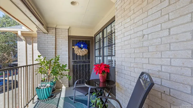 a balcony with table and chairs and potted plants