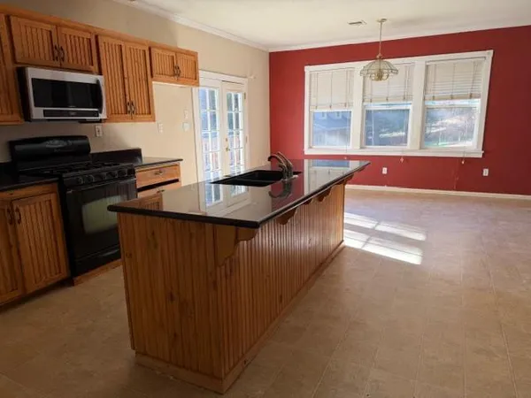 a kitchen with stainless steel appliances granite countertop a sink a granite counter tops and a view of living room
