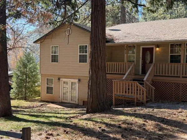a view of a house with a small yard and wooden fence and trees