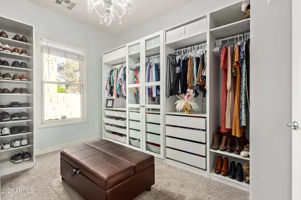 a view of walk in closet with clothes and shoes