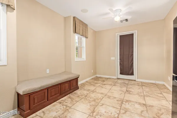 a view of an empty room with window and chandelier fan