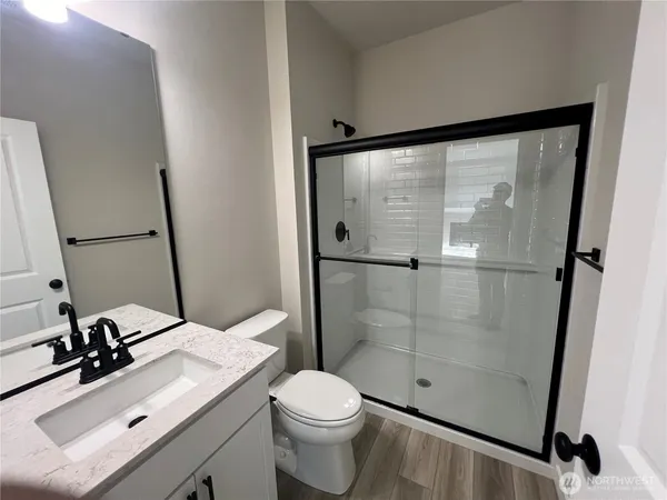 a bathroom with a granite countertop sink a mirror and shower