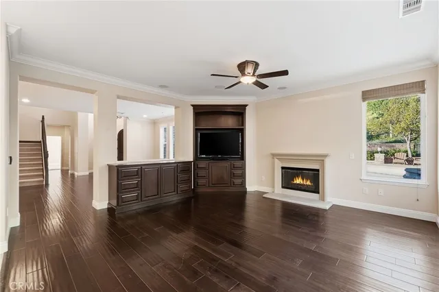 an empty room with wooden floor fireplace and windows