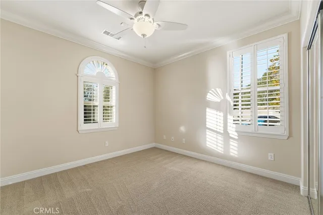 an empty room with windows and chandelier fan