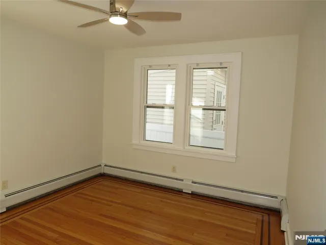 an empty room with wooden floor fan and windows