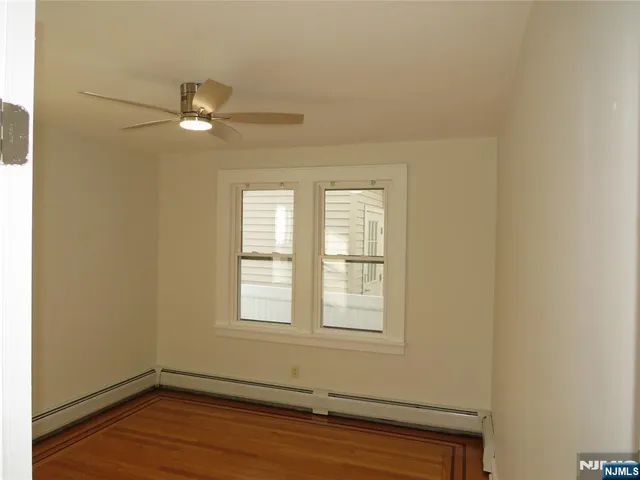 an empty room with wooden floor fan and windows
