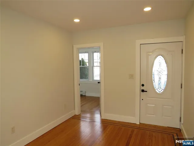 an empty room with wooden floor mirror and window