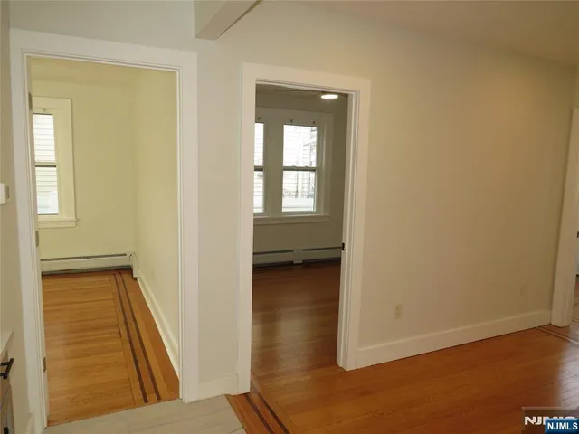 a view of a hallway with wooden floor and a living room