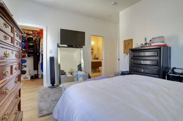 a bedroom with a large bed and a flat tv screen