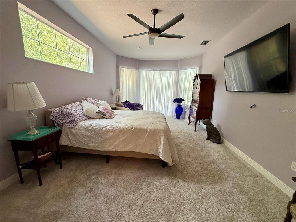13110 Bamboo Street Spring Hill, FL 34609 - Photo 29 of 56 a bedroom with a bed a couch and a flat screen tv