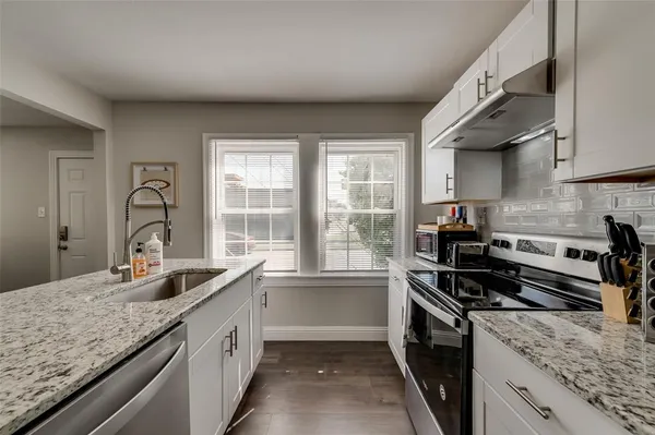 a kitchen with granite countertop a sink and a stove top oven