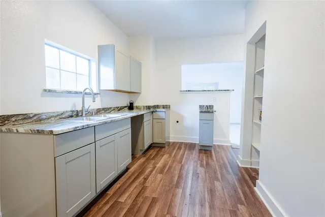 a kitchen with a sink wooden floor and a window