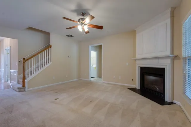 a view of an empty room with chandelier fan